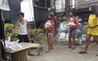<p><strong>LITTLE PASTOR</strong>. Jhon Rhod Amodia (left), 13, gives out relief packs to his neighbors in Barangay Gabi, Cordova, Cebu during the enhanced community quarantine. The Department of Social Welfare and Development (DSWD)-Central Visayas on Tuesday (June 2, 2020) commended Amodia, the regional winner of the 2019 Exemplary Pantawid Pamilya Children, for his good deeds despite coming from an indigent family.<em> (Photo courtesy of DSWD-7)</em></p>