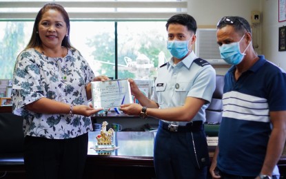 <p><strong>TOWN RECOGNITION</strong>. Baroy Mayor Rosa Olafsson (left) presents a plaque of recognition to PMA 9th placer 2Lt. Rubenson Prajes Abgao as his father, Rodrigo Abgao, looks on. (J<em>. Umaran/HRS Media</em>)</p>