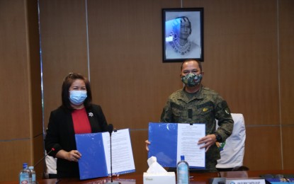 <p><strong>MOA FOR TROOPS' BENEFITS.</strong> AFP chief-of-staff, Gen. Felimon Santos Jr. (right), and ECC executive director Stella Zipagan-Banawis (left) show a copy of the signed memorandum of agreement in a ceremony in Camp Aguinaldo, Quezon City on Monday (June 15, 2020). Under the agreement, the ECC will conduct seminars on the Employees’ Compensation Program (ECP), facilitate information exchange, and assist in the provision of services for qualified AFP personnel or their beneficiaries. <em>(Photo courtesy of AFP Public Affairs Office)</em></p>