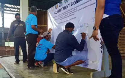 <p><strong>COMMITMENT OF SUPPORT.</strong> Members of the indigenous Manobo-Dulangan community (in blue shirts) and other community stakeholders sign the commitment of peace tarpaulin following a gathering of the Municipal Task Force to End Local Communist Armed Conflict in Kalamansig, Sultan Kudarat on Friday (June 26, 2020). The IP leaders denounced the communist New Peoples’ Army and vowed to support all peace and development programs of the government.<em> (Photo courtesy of 37IB)</em></p>