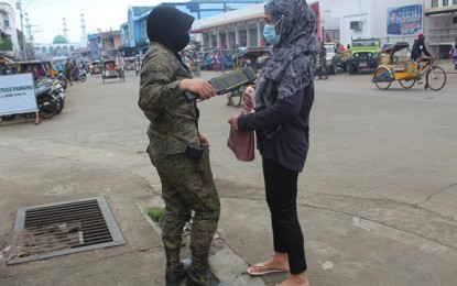 <p><strong>SECURITY DUTY.</strong> A female Tausug soldier checks on the bag of a pedestrian in downtown Jolo, the capital of Sulu, following the decision of the Army's 11th Infantry Division to deploy female Tausug soldiers to render security in the area. The deployment of female soldiers is also in line with the command's policy on gender equality in service, an official says. <em>(Photo courtesy of the 11th Infantry Division)</em></p>