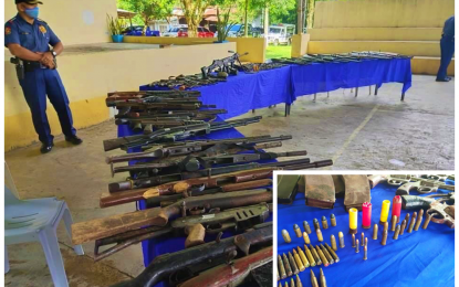 <p><strong>SURRENDERED WEAPONS</strong>. A police officer stands guard during the official presentation of the surrendered firearms, grenades, and ammunition (inset) at the North Cotabato Provincial Police Office headquarters in Kidapawan Coty on Tuesday (June 30, 2020). The NCCPO said the weapons came from illegal gun holders across the province that were handed over to their respective local government units under the provincial police’s 'Tugro Pusil' project, a localized version of the national government’s 'Balik Baril' program. <em>(Photo courtesy of NCCPO)</em></p>