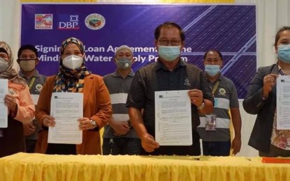 <p><strong>WATER SUPPLY.</strong> Taraka Mayor Nashimba Sumagayan (2nd from left), Mindanao Development Authority (MinDA) Secretary Emmanuel Piñol and Development Bank of the Philippines (DBP) representative Angelita Aguhob (right) show the signed documents of the PHP218 million worth loan agreement for the Mindanao Water Supply Program in Taraka, Lanao del Sur on Tuesday (June 30, 2020). Part of the loan will also be used to buy infrastructure equipment to build road networks in the town. <em>(MinDA photo)</em></p>