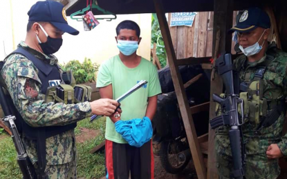 <p><strong>ARRESTED.</strong> A police officer reads the 'Miranda doctrine' to suspected New People’s Army rebel Ronilo Ansabo (center) after a law enforcement operation in Magpet, North Cotabato, on Thursday (July 2, 2020). Authorities found guns, explosives, and medical kits inside the suspect’s home. <em>(Photo courtesy of DXND – Kidapawan)</em></p>