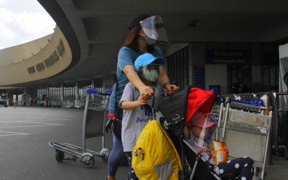 <p><strong>OUTBOUND TRAVEL.</strong> A woman and two children, donning face masks and shield, arrive at the Ninoy Aquino International Airport in this file photo. Non-essential outbound travel of Filipinos is now allowed effective October 21, Malacañang said Friday. <em>(PNA photo by Avito C. Dalan)</em></p>