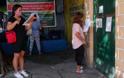 <p><strong>ENROLLMENT.</strong> Parents wait in front of the gate of Quezon City High School along Scout Ybardolaza St. in Quezon City on June 15, 2020. The Department of Education has allowed the conduct of "physical" enrolment in schools in June subject to health protocols such as wearing of face masks and safe physical distancing measures. <em>(PNA photo by Robert Oswald P. Alfiler)</em></p>