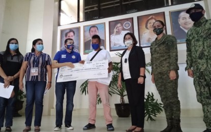 <p><strong>NEW LIFE</strong>. Alias "Ben" (center) receives a check worth PHP104,000 from Bohol Governor Arthur Yap in a simple ceremony in the Municipality of Trinidad, Bohol on Tuesday (July 14, 2020). Ben, who surrendered in 2018 after years of living a troubled life as member of the Communist Party of the Philippines-New People's Army, vowed to use the cash aid to start fresh as a law-abiding resident of Bohol<em>. (Photo courtesy of 47th Infantry Battalion-CMO)</em></p>