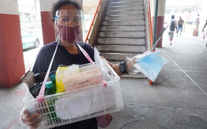 <p><strong>HEALTH PROTOCOLS.</strong> Karen Miranda wears face mask and face shield to protect herself from infectious coronavirus disease while selling health and safety items under a footbridge in Cubao, Quezon City on Monday (July 20, 2020). A recent UK think thank YouGov survey showed that 91 percent of Filipinos wear face masks whenever they are outside of their homes. <em>(PNA photo by Robert Oswald P. Alfiler)</em></p>