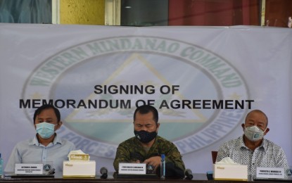 <p><strong>AID TO ISLAND COMMUNITIES.</strong> Jaythoon Sahibul of the Mask-Agri Marine Producer Cooperative (left) and Lourdes Fishing Company Inc. general manager Perfecto Mendoza III (right) sign an agreement Friday (July 24, 2020) to help island communities within the area of Western Mindanao Command (Westmincom). Lt. Gen. Cirilito Sobejana, Westmincom chief, witness the pact signing held at the command's headquarters. <em>(Photo courtesy of Westmincom Public Information Office)</em></p>