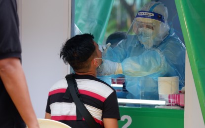 <p><strong>SWAB TEST.</strong> A man undergoes swab testing in Quezon City in this undated photo. The Department of Tourism encourages travelers to avail themselves of the 50 percent subsidized RT-PCR tests at the University of the Philippines-Philippine General Hospital for PHP900. <em>(PNA file photo by Robert Alfiler)</em></p>