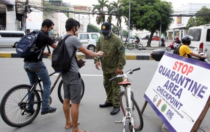 <p><strong>INSPECTION</strong>. A cyclist shows an ID to a Cainta police officer manning a checkpoint along Felix Avenue in Cainta, Rizal on Wednesday (August 5, 2020). Many workers ride bicycles to go to their workplaces as public transport has been suspended anew in Metro Manila and neighboring provinces under the modified enhanced community quarantine until August 18<em>. (PNA photo by Joey O. Razon)</em></p>