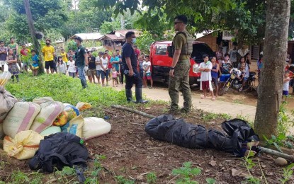 <p><strong>ANOTHER WASTED LIFE.</strong> Residents of Barangay Bal-ason, Gingoog City, Misamis Oriental, gather to look on as Army's 58th Infantry Battalion (58IB) personnel gather near the wrapped body of a rebel, later identified as Brenda Serenio, 24. On Aug. 13, the Army unit had an encounter with around 20 NPA rebels in the area.<em> (Photo courtesy of 58IB)</em></p>