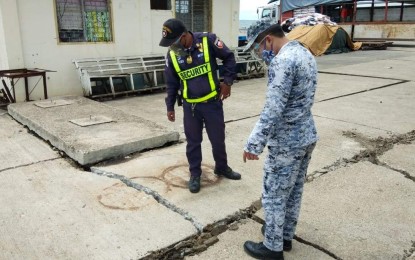 <p><strong>DAMAGES AT CATAINGAN PORT. </strong> A port security officer and a member of the Philippine Coast Guard (PCG) assess the extent of damage caused by a 6.5-magnitude earthquake at Cataingan Port on Tuesday (August 18, 2020). The PCG said the port has resumed operations with no recorded injuries or fatalities. (<em>Photo courtesy of PCG</em>) </p>