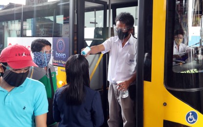<p><strong>FREE BEEP CARDS.</strong> Passengers undergo a temperature check before boarding a bus in this file photo. AF Payments, Inc., the provider of contactless electronic payment system beep cards, has committed to giving 125,000 free cards to Edsa Busway commuters.<em> (PNA photo by Joey Razon)</em></p>
