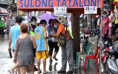 <p><strong>BARANGAY CHECKPOINT.</strong> A barangay personnel checks the identification of a resident in Quezon City. Metro Manila and the provinces of Bulacan, Batangas and the city of Tacloban are under general community quarantine. <em>(File photo)</em></p>