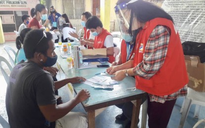 <p><strong>CASH AID VIA TEXT.</strong> Director Rebecca Geamala (right), of the Department of Social Welfare and Development (DSWD) in Region 7, assists a SAP beneficiary in Tabogon, a northern town in Cebu province, during the payout to some 1,297 waitlisted beneficiaries on Aug. 22, 2020. Geamala said those who have no smartphones can use their basic or non-Android cellphone to claim their SAP subsidy via SMS (short message service) or text message through PayMaya<em>. (Photo courtesy of DSWD-7)</em></p>