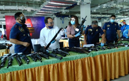 <p><strong>SEIZED.</strong> Government and law enforcement officials inspect seized firearms during a press briefing at the Palayan City Business Hub in Nueva Ecija on Friday (Aug. 28, 2020). (From left to right) Police Regional Office 3 director Brig. Gen. Rhodel Sermonia, PTFoMS executive director Joel Sy Egco and Palayan City Mayor Adrianne Mae Cuevas.<em> (Photo by Marilyn Galang)</em></p>