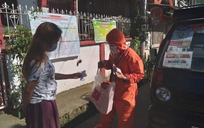 <p><strong>E-MARKET.</strong> A woman in Catbalogan City in Samar receives the goods she purchased from the city's e-market. The city government on Wednesday (Sept. 9, 2020) said they reactivated the e-market program to combat the spread of Covid-19.<em> (Photo courtesy of Catbalogan City government)</em></p>