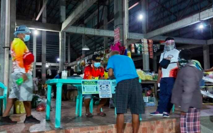 <p><strong>HEALTH PROTOCOLS.</strong> Market-goers at the Vintar public market take turns in registering and having their body temperature checked before entering the market in this undated photo. The local government unit of Vintar, Ilocos Norte on Friday (Sept. 11, 2020) asked its returning residents to postpone their travel as all quarantine facilities in the municipality and province are occupied. <em>(File photo courtesy of Vintar Balay ti Ili Facebook page)</em></p>