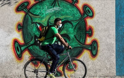 <p><strong>FIGHT VS. COVID.</strong> A man wearing a face mask rides past a mural depicting the coronavirus to draw attention and raise awareness to the fight against the Covid-19 pandemic in Gaza Strip, Gaza Saturday (Oct. 3, 2020). Around 10 percent of the world's population may have already been infected with Covid-19, the World Health Organization's chief of emergencies said. <em>(Mustafa Hassona/Anadolu photo)</em></p>