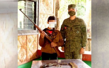 <p><strong>SURRENDER</strong>. Lt. Col. Angelo Guzman, commander of 94th Infantry Battalion, is shown before he receives a .30-caliber Springfield sniper rifle from 16-year-old alias “Jacking”, a former combatant of the New People’s Army assigned as medical officer of Sentro De Gravidad Platoon of Central Negros Front 2. Together with his father, who turned over a .38-caliber pistol, the boy surrendered to the 94IB troops on Oct. 9, 2020.<em> (Photo courtesy of 94th Infantry Battalion, Philippine Army)</em></p>