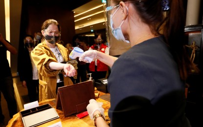 <p><strong>CHECK-IN</strong>. Tourism Secretary Bernadette Romulo-Puyat undergoes a temperature check during the inspection of the Grand Hyatt Hotel in BGC Taguig City on Oct. 14, 2020. Around 7,200 hotels and resorts have so far been allowed to operate since the first community quarantine was imposed in the country.<em> (PNA photo by Avito C. Dalan)</em></p>