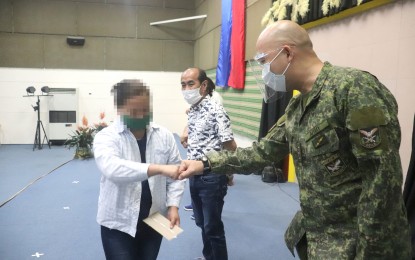 <p><strong>FINANCIAL AID.</strong> A former member of the New People's Army (left) receives financial assistance from the officials of the Armed Forces of the Philippines, the Davao de Oro provincial government, and the Department of Social Welfare and Development on Tuesday (Oct. 13, 2020) in Nabunturan town. Each rebel returnee received PHP20,000 and an additional PHP4,000 as food assistance. <em>(Photo courtesy of 1001IB)</em></p>