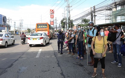 <p><strong>MONDAY COMMUTE.</strong> Passengers wait to board a bus at a pick-up point along Quirino Highway in Novaliches, Quezon City on Monday (Oct. 19, 2020). The Metro Manila Council has agreed to recommend adjusting the curfew hours in Metro Manila from 8 p.m. - 5 a.m. to 12 a.m. - 4 a.m., except in Navotas City, allowing persons 18 to 65 years old to go outside their residences, and increasing the capacity of churches to 30 percent. <em>(PNA photo by Oliver Marquez)</em></p>