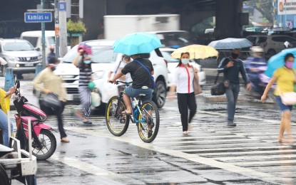 <p><strong>UNDER THE UMBRELLA</strong>. Pedestrians and a cyclist in Quezon City use their umbrellas to protect themselves from rain showers in this undated file photo. Several areas in the country will experience scattered rains due to the trough of a low pressure area outside the Philippine Area of Responsibility and southwest monsoon or "habagat", a forecaster said Monday (Sept. 25, 2023). <em>(File photo) </em></p>
