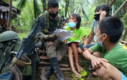 <p><strong>COMBATANT MENTOR.</strong> A police officer of the 2nd Surigao del Norte Provincial Mobile Force Company puts away his high-powered firearm to mentor the elementary schoolchildren in Sitio Tigasi, Barangay Dugsangon in Bacuag, Surigao del Norte on Oct. 18, 2020. The pioneering initiative--dubbed as 'combatant mentors' project--is being mulled for possible adoption among all police units in the entire Caraga Region. <em>(Photo courtesy of PRO-13 Information Office)</em></p>