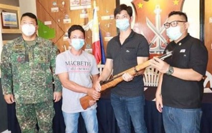 <p><strong>SURRENDER.</strong> A member of the Abu Sayyaf Group identified as Berhamin Kalinggalan (2nd from left) turns over a Garand rifle to Mayor Jimuel Que of Bongao, Tawi-Tawi (2nd from right), when he surrendered Thursday (Oct. 22, 2020) to the 2nd Marine Brigade. Kalinggalan was involved in the attempted abduction of Dr. Percival Showers, an American-Nigerian and guest professor of the Mindanao State University-Tawi-Tawi in 2001. <em>(Photo courtesy of the 2nd Marine Brigade)</em></p>