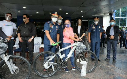 <p><strong>BIKE TO WORK.</strong> A worker receives a free bicycle from PNP Chief, Gen. Camilo Cascolan (3rd from left), during the launch of the “PADYAKabuhayan” program in Camp Crame on Friday (Oct. 30, 2020). The “PADYAKabuhayan” is a new component of the Barangay Covid Defense initiative of the PNP that aims to help workers whose jobs have been affected by the limited operations of public transport due to the Covid-19 lockdown.<em> (Photo courtesy of PNP Public Information Office)</em></p>
