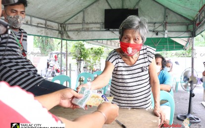 <p><strong>SENIORS' BENEFITS. </strong>An elderly in Tarlac City, Tarlac receives her year-end benefit from the city government on Monday (Nov. 9, 2020). Some 38,000 senior citizens in the city will receive their year-end benefits, which Mayor Cristy Angeles said is her administration's early Christmas treat to the elderlies during this Covid-19 pandemic.<em> (Photo by the City Government of  Tarlac)</em></p>