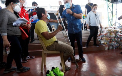 <p><strong>MARIKINA VISIT.</strong> Senator Christopher Lawrence Go (in blue polo shirt) talks to a resident of Barangay Tumana after giving him a pair of shoes in an evacuation center in Hermogenes Bautista Elementary School in Conception, Marikina City on Monday (Nov. 16, 2020). Go, accompanied by Social Welfare Secretary Rolando Bautista, Trade Secretary Ramon Lopez, and Mayor Marcelino Teodoro, led the distribution of relief goods and financial assistance to some 4,109 individuals affected by Typhoon Ulysses. <em>(PNA photo by Avito C. Dalan)</em></p>