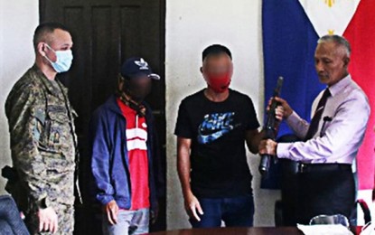 <p><strong>SURRENDER.</strong> Two supporters of the Islamic State for Iraq and Syria-inspired Dawla Islamiyah surrender Tuesday (Nov. 24, 2020) to government authorities in Madalum town, Lanao del Sur. Photo shows one of the two surrenderers handing over a rifle to Prof. Cosain Umpa, a consultant of the Madalum municipal government, who negotiated for the surrender of the two. <em>(Photo courtesy of the Army's 55th Infantry Battalion)</em></p>