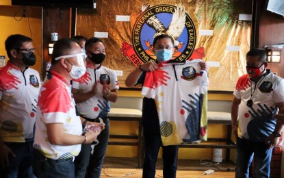 <p><strong>SERVICE AWARD</strong>. Senator Christopher Lawrence "Bong" Go receives his club uniform from the officers of the Cebu Central Eagles Club led by charter president John Rey Saavedra, after approving en masse a resolution adopting him to the club. For his efforts in opening 95 Malasakit Centers nationwide, the Cebu Central Eagles Club which was chartered on Friday night (Dec. 18, 2020), commended Go through a Service Award. <em>(Contributed photo)</em></p>