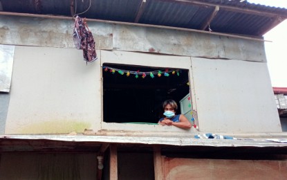 <p><strong>GETTING BY.</strong> Gina Tinedero sits by her window reminiscing the traumatic episode on Nov. 11, the day when Typhoon Ulysses battered her community in Marikina City. Her house was covered with mud and dirt from when the Marikina River overflowed due to the heavy rains brought by Ulysses.<em> (Photo by Raquel Bonustro) </em></p>