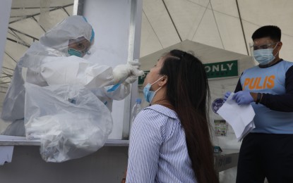 <p><strong>UPDATED TESTING POLICY.</strong> A woman undergoes a swab test at a testing center in Manila in this undated photo. Malacañang announced on Tuesday (June 28, 2022) that unvaccinated employees required to do on-site work in areas under coronavirus disease 2019 (Covid-19) Alert Level 1 classification will no longer be required to undergo real-time-polymerase chain reaction testing. <em>(PNA file photo by Avito Dalan)</em></p>