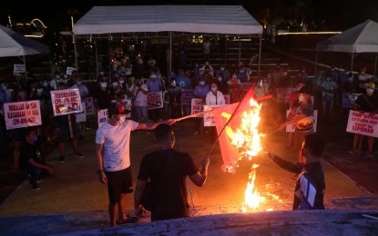 <p><strong>INDIGNATION RALLY</strong>. Demonstrators burn flags of the communist-terrorist group to show their abhorrence of its acts of evil, during an indignation rally at the Peñaranda Freedom Park in Legazpi City on Wednesday (Jan. 20, 2021). A candle-lighting activity was also held while prayers were offered for the souls of all the victims of the five-decade armed struggle. <em>(Photo courtesy of the 9th Infantry Division, PA)</em></p>