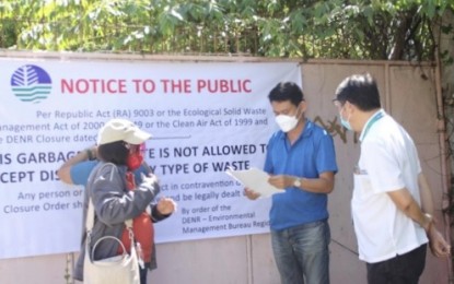 <p><strong>OPEN DUMPSITES CLOSED</strong>. Officials of the Environmental Management Bureau in Central Visayas mount a closure notice in front of the open dumpsite in Barangay Luyang, Carmen, Cebu after the actual padlocking of the gate on Monday (Jan. 25, 2021). The EMB-7 also simultaneously served a closure order to another open dumpsite in Guindulman town in Bohol. <em>(Photo courtesy of EMB-7)</em></p>