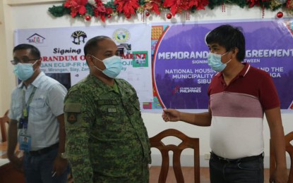 <p><strong>HOUSING PROJECTS.</strong> Mayor Jarvis Acosta (right) of Siay, Zamboanga Sibugay, and Maj. Cyril Noel Ates, the Army's 44th Infantry Battalion (IB) executive officer, confer with each other after the signing Thursday (Feb. 4, 2021) of a memorandum of agreement with the National Housing Authority for the implementation of two housing projects for former New People's Army rebels and supporters, and indigenous peoples. Also in photo is Engr. Al-Khwarizmi Indanan, NHA district manager. <em>(Photo courtesy of the 44th IB)</em></p>
