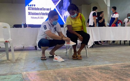 <p><strong>ASSISTANCE.</strong> Senator Christopher Lawrence 'Bong' Go gives a pair of new shoes to Rosario Anecito, a fisherman in the Island Garden City of Samal (Igacos), Davao del Norte, on Thursday (Feb. 18, 2021). Joined by national government agencies, Go handed out assistance to the island's fisherfolk to cushion the impact of the coronavirus disease pandemic. <em>(PNA photo by Prexx Marnie Kate Trozo)</em></p>