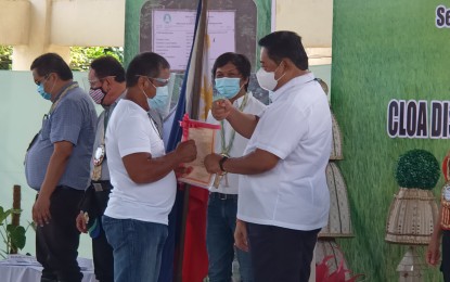 <p><strong>NEW LANDOWNERS</strong>. Department of Agrarian Reform Secretary John Castriciones (right) handing over a certificate of land ownership to a farmer during a ceremony in Tacloban City on Wednesday (March 3, 2021). At least 88 agrarian reform beneficiaries from eight towns in Leyte province and this city received their land titles from the Department of Agrarian Reform during the event.<em> (PNA photo by Roel Amazona)</em></p>