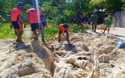 <p><strong>GIANT CLAMS SEIZED.</strong> Personnel of the Philippine Coast Guard (PCG) dig up shells of endangered giant clams along a beach at Barangay VI, Johnson Island, Roxas in Palawan on March 3, 2021. The PCG on Friday (March 5, 2021) said the seizure, a haul of around 80 tons of giant clam shells, was the biggest of its kind in Palawan. <em>(Photo courtesy of PCG)</em></p>