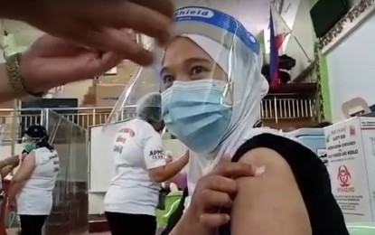 <p><strong>GETTING THE JAB.</strong> Norhaisa Aragon, a staff nurse at the state-run Amai Pakpak Medical Center in Marawi City, holds a cotton swab where the Covid-19 vaccine was injected on her on Monday (March 8, 2021). She says that she is getting the vaccine to protect her parents, who have always doubted the existence of the coronavirus disease. <em>(PNA photo by Divina Suson)</em></p>