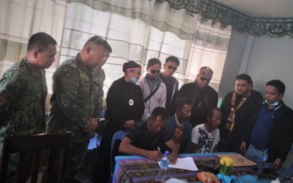 <p><strong>RECONCILED.</strong> Two warring clans in Tawi-Tawi province settle their eight-year-old dispute Monday (March 8, 2021) in a ceremony at the provincial capitol. Military officials led by Brig. Gen. Arturo Rojas, Joint Task Force Tawi-Tawi commander (2nd from left, standing), and other government officials witness the signing of the peace agreement.<em> (Photo courtesy of the Western Mindanao Command Public Information Office)</em></p>