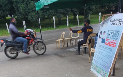 <p><strong>DISINFECTION.</strong> A barangay enforcer (right) on Wednesday (March 10, 2021) directs a motorist to undergo disinfection before entering Barangay Pagatpat, in Cagayan de Oro City. The policy has been in place since February as Barangay Pagatpat is one of the 16 villages in the city which recorded a positive case of African swine fever involving backyard hogs.<em> (PNA photo by Nef Luczon)</em></p>