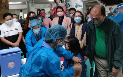 <p><strong>CEREMONIAL VACCINATION</strong>. Quezon Governor Danilo Suarez (standing, right) witnesses the ceremonial vaccination against Covid-19 of Dr. Allen Logatoc, chief of the Quezon Medical Center's Infectious Diseases Department, in Lucena City on Thursday (March 11, 2021). The province received 1,790 doses of Sinovac vaccines on March 10. <em>(Photo by Belinda Ortodoz)</em></p>