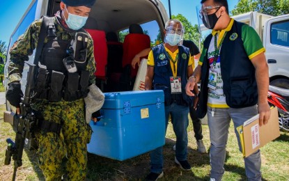 <p><strong>MORE VACCINES</strong>. A police officer and staff member of the Department of Health-Region 12 carry the cooler box containing the 84 vials or equivalent to 840 doses of AstraZneca vaccines for General Santos City upon arrival before noon on Monday (March 15, 2021) at the cold storage facility inside the city gymnasium in Baragay Lagao. A total of 748 frontline health workers from 10 public and private hospitals in the city are eligible to receive the vaccines. (<em>Photo courtesy of the city government</em>)  </p>