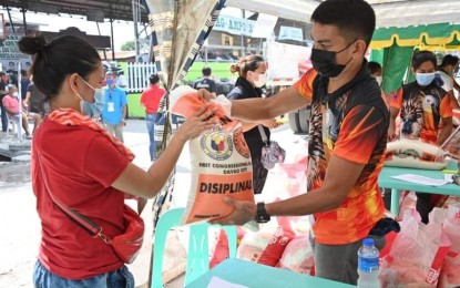 <p><strong>AID TO FIRE VICTIMS.</strong> A staff of Davao City First District Rep. Paolo "Pulong" Duterte (right) hands over a bag of rice to a fire victim in Barangay Vicente Duterte in Agdao District on Saturday (March 13, 2021). The relief distribution benefited over 400 families.<em> (Photo courtesy of 1st Dist. Rep. Paolo 'Pulong' Duterte's office)</em></p>